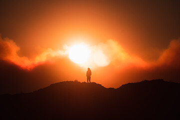 silhouette of a person in front of the sun on rocks