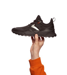 A man's hand holding a trendy black sneaker isolated on a white background. Creative minimalistic...