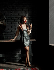 Feminine young black woman standing in her modern apartment and drinking wine. Succesful life...