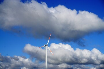 Windmühle vor blauem Himmel mit riesigem weißen Wolkengebilde bei Sonne am Morgen im Sommer 