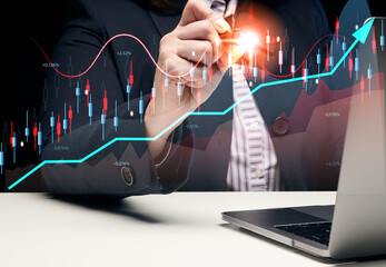 Woman sits at a laptop in front of a holographic chart with growing indicators. Business...