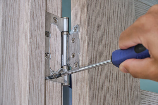 Repair and installation door hinges with screwdriver.