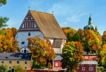 Trees at autumn colors at the historical city center of Porvoo Finland. Old medieval middle age church and old wooden buildings. Red and yellow trees. Color composition. 