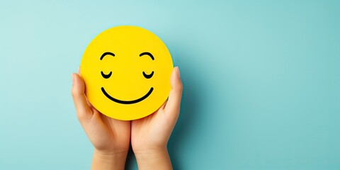 World Mental Health Day. Hands holding a happy smile, round yellow ball, on a blue background, relax face, good feedback rating, think positively. Place for text. - obrazy, fototapety, plakaty