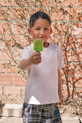 Fototapeta premium vertical photo of latin boy inviting an ice cream in summer on hot day in bolivia
