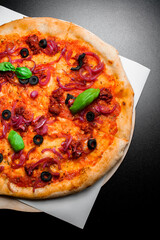 Appetizing and tasty vegetable pizza with red onion, black olives, sun dried tomatoes and basil