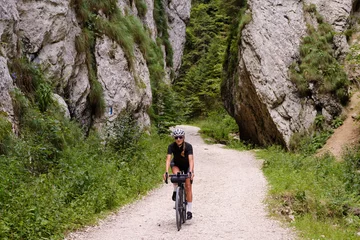 Foto op Canvas Female cyclist riding a gravel bike through rocky mountain terrain. Gravel biking adventure on beautiful mountain trails. Outdoor sport activity.Fit pretty cyclist training on nature. © Ketrin
