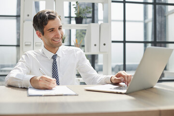 young businessman in a white shirt and tie working in a modern office.