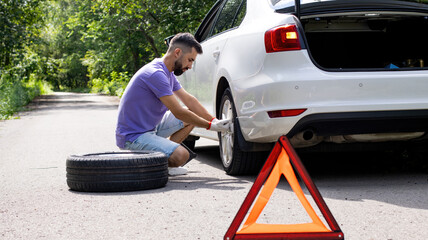 Installing or replacing a car's spare wheel on the side of the road or the edge of the road. Young...
