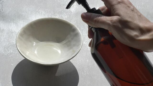 Base oil pouring from bottle to bowl on wooden background 