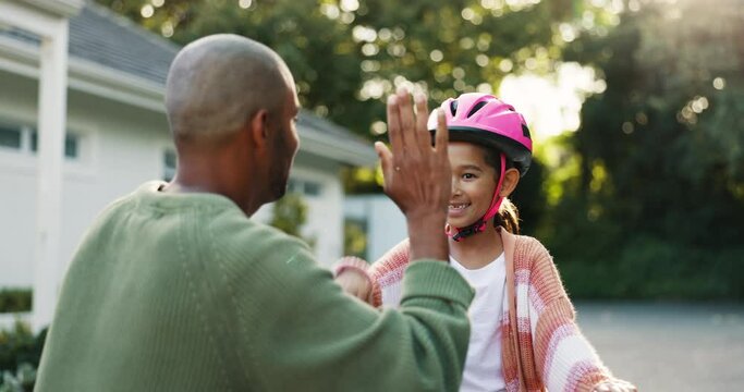Dad, girl child and high five with bike, helmet and safety with teaching, celebration or motivation for goal. Father, daughter and bicycle outdoor in street with learning, helping hand and support