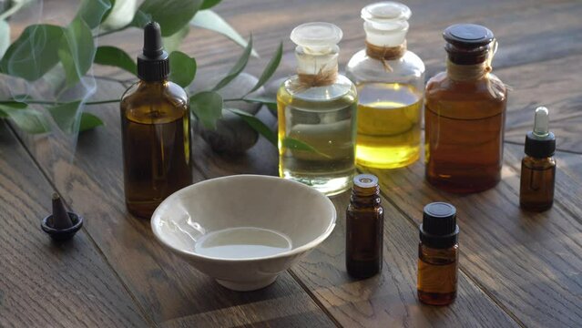 Essential oils in various bottles on wooden background with incense cone 