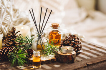Home aromatherapy with pine cedar oil extracts, essential oil, extract, essence on wooden table. Cozy home atmosphere, natural decor and fragrance. Relaxation, mediation. Apartment design, candles - obrazy, fototapety, plakaty