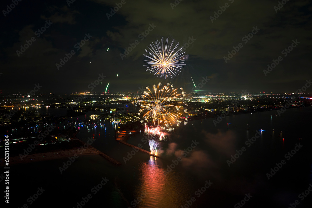 Wall mural Aerial view of bright fireworks exploding with colorful lights over sea shore on US Independence day holiday - Wall murals