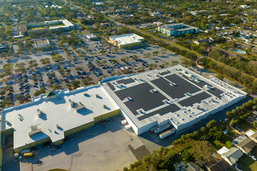 Aerial view of blue photovoltaic solar panels mounted on shopping mall building roof for producing...