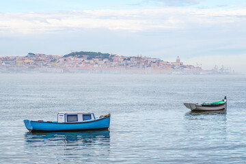 Fototapeta na wymiar Boats in Tagus river on misty morning with Lisbon in background with mist