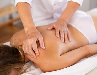 Female patient having general back massage lying at massage table