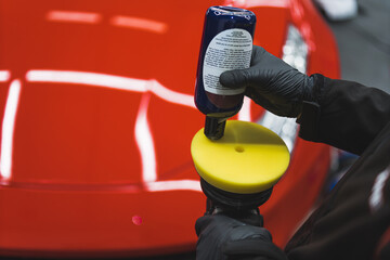 closeup shot of a mechanic adding liquid on an orbital polisher to use on a car at the repair shop. High quality photo