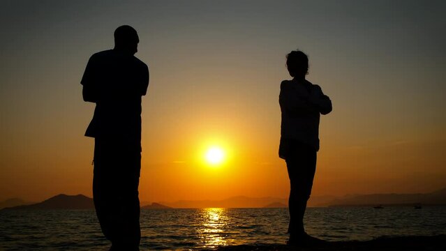 Man and woman silhouette after quarrel. Silhouettes of man with his wife on the beach against dusk sky. A concept of family with understanding problems.