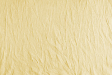 Wrinkled, crumpled yellow fabric texture background. Wrinkled and creased abstract backdrop of cotton jersey textile, wallpaper with copy space, top view.
