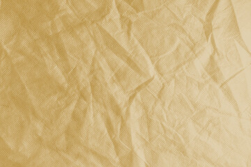 Wrinkled, crumpled yellow fabric texture background. Wrinkled and creased abstract backdrop of spunbond textile, wallpaper with copy space, top view.