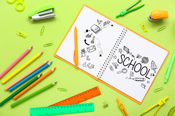 Notebook with word SCHOOL and different stationery on green background