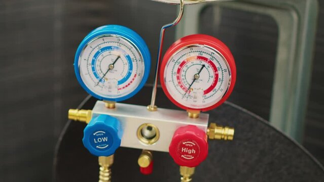 Close up shot of professional ac gauges vacuum pump used for checking HVAC system freon. Set of manometers showing high or low refrigerant levels in external air conditioner