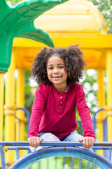 Smiling cute little african american girl with curly hair looking at camera. Portrait of happy African American girl playing in the park. - 633162463