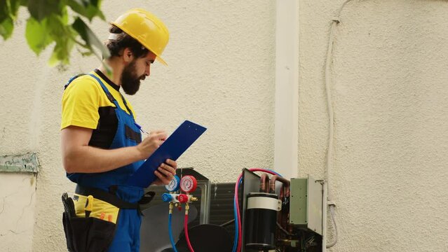 Certified technician contracted by customer to detect air conditioner issues, writing down on clipboard real-time superheat and subcooling values measured by pressure benchmarking tool