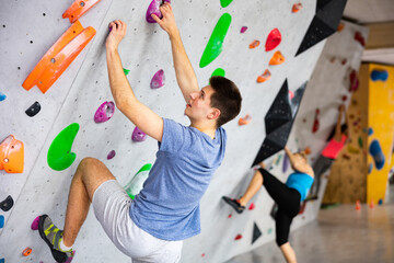 Sporty man training at bouldering gym without special climbing equipment