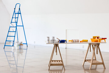 Table with paint cans and rollers in room