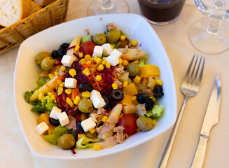Portion of fresh mediterranean salad made of olives, corn, beetroot, feta cheese, meat, carrot and beetroot.