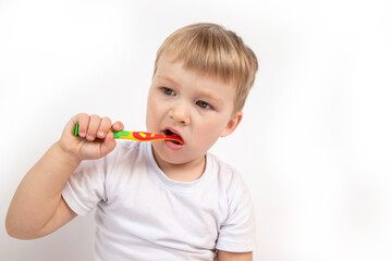 Child with a toothbrush on a white background diligently brushes his teeth close-up portrait. the concept of caring for children's milk teeth, personal hygiene procedure.