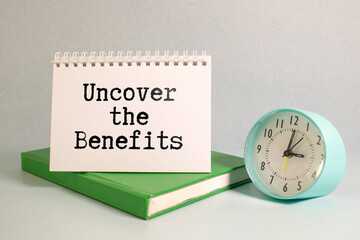 Green plant and notebook with the word UNCOVER THE BENEFIT on green background