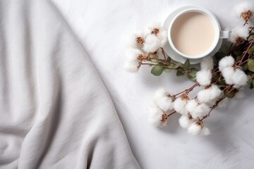 Obraz na płótnie Canvas This is a top down view of a composition in the cozy minimalism style. It includes a warm blanket, a cup of herbal tea, cotton flowers, and eucalyptus twigs, all placed on a white concrete background