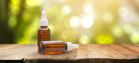 amber glass facial serum bottles with pipette on a tabletop and a refreshing green background,...
