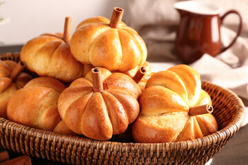 Wicker bowl with tasty pumpkin shaped buns on table