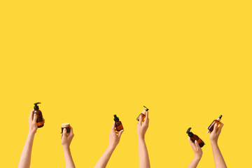 Women with cosmetic products on yellow background