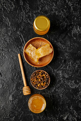 Composition with tasty honey, combs and beebread on dark background