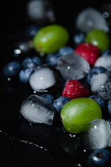 berries with ice cubes on a black background