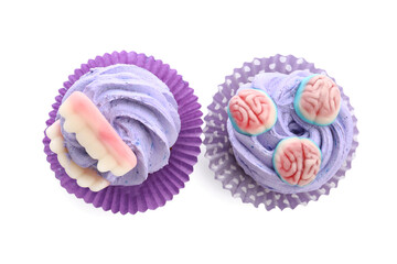 Different delicious Halloween cupcakes with candies on white background