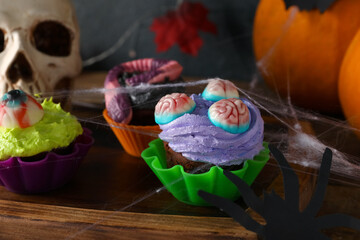 Board with delicious Halloween cupcakes on wooden background, closeup