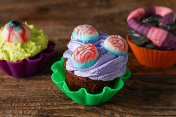 Delicious Halloween cupcakes on wooden background, closeup