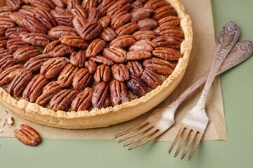 Tasty pecan pie on green background