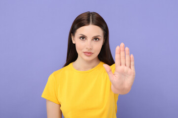 Woman showing stop gesture on violet background