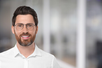 Handsome confident man with eyeglasses in office, space for text