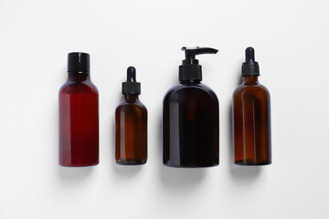 Bottles with different cosmetic products on white background, flat lay