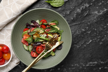 Delicious vegetable salad served on black textured table, flat lay. Space for text
