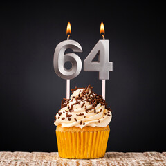 Birthday candle number 64 - Anniversary cupcake on black background