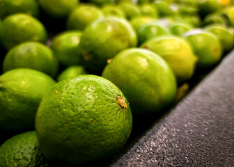 A row of bright green limes on sale, fresh food organic produce background.